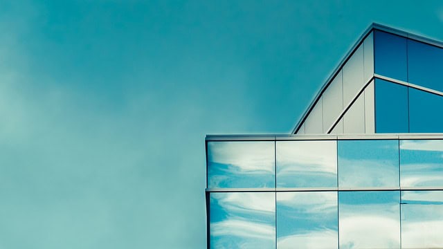 Office building with reflective glass facade and blue sky background.