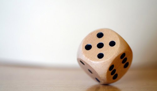 Dice with black dots on a light wooden surface for gaming or decision-making.