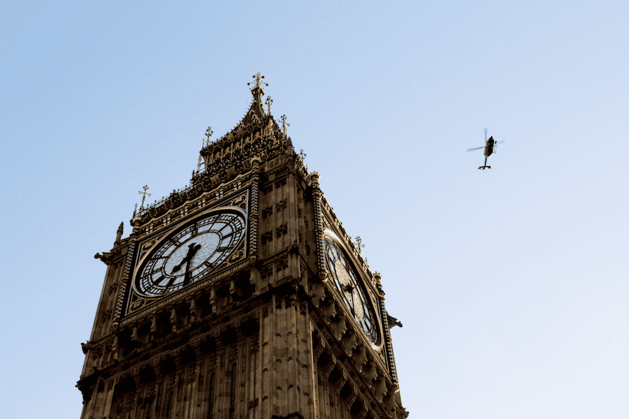 Iconic Big Ben clock tower in London with a helicopter flying nearby.