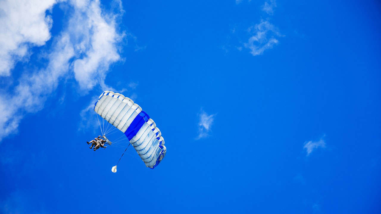 Quantilia logo with parachute against blue sky with clouds.