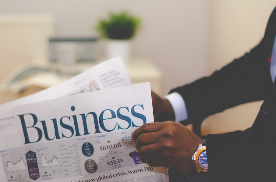 Business professional analyzing financial newspaper for market insights.