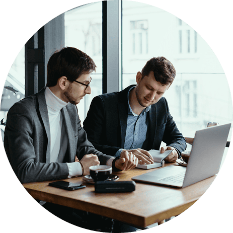 Two professionals reviewing portfolio data on laptop with financial analytics dashboard