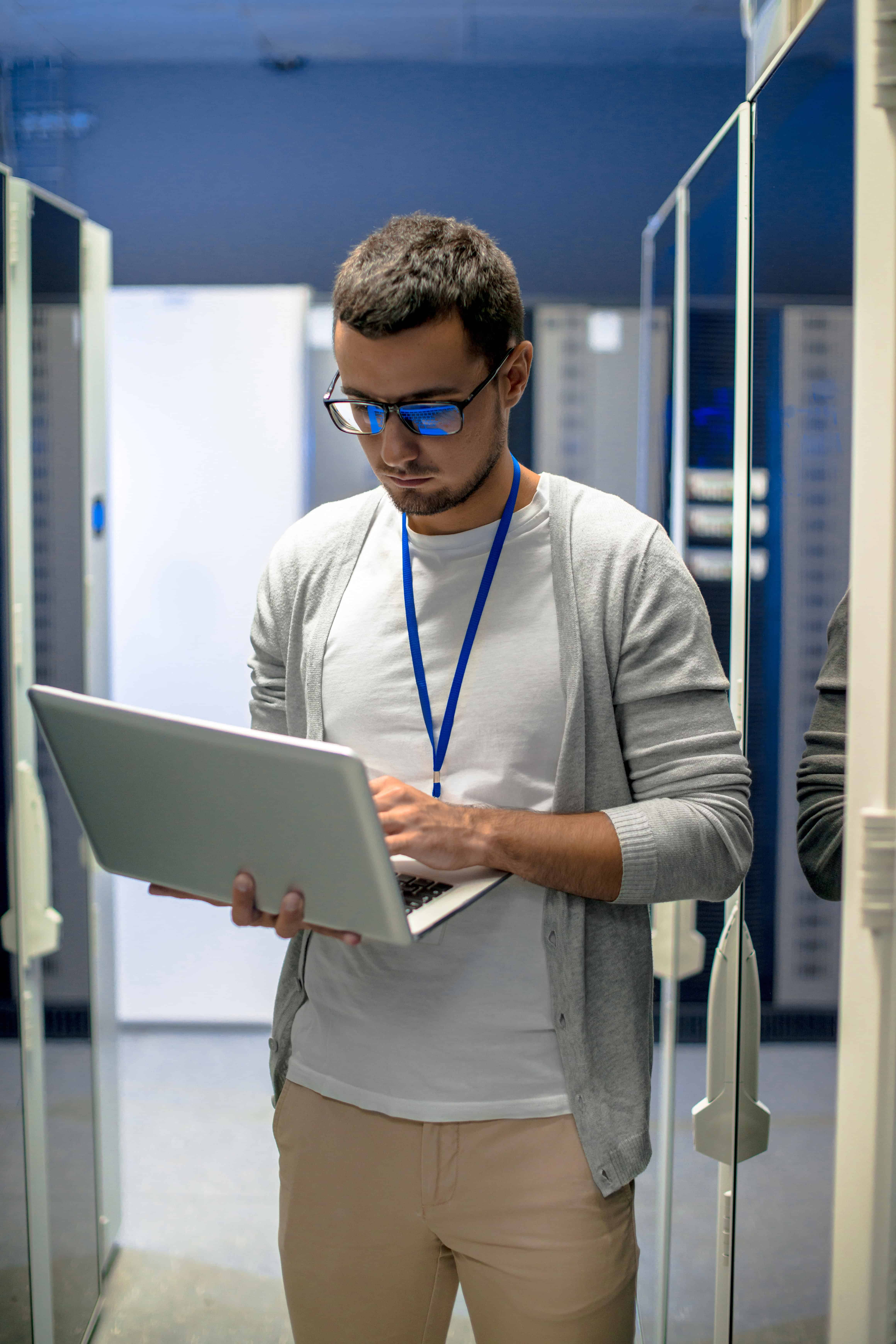 Data center technician working on a laptop in server room.